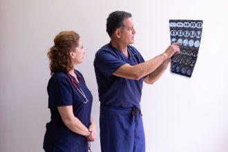 Dois profissionais de saúde examinam uma radiografia em um ambiente hospitalar.