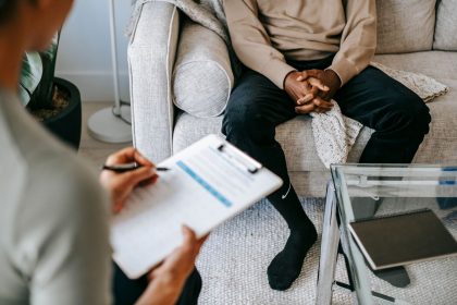 Terapeuta faz anotações durante uma consulta com um paciente em um consultório de saúde mental.