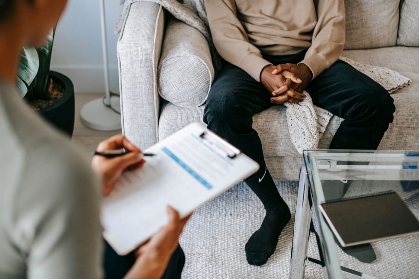 Terapeuta faz anotações durante uma consulta com um paciente em um consultório de saúde mental.