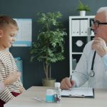 Médico conversa com uma mãe e uma criança durante uma consulta em uma clínica.