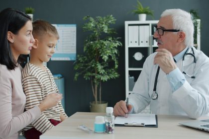 Médico conversa com uma mãe e uma criança durante uma consulta em uma clínica.