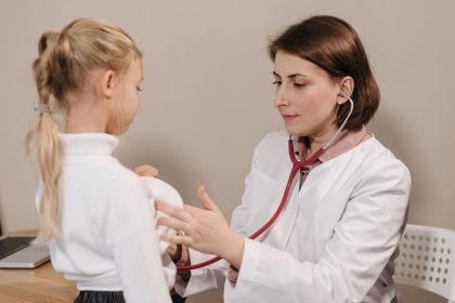 Médico examina uma criança com um estetoscópio durante um atendimento clínico.