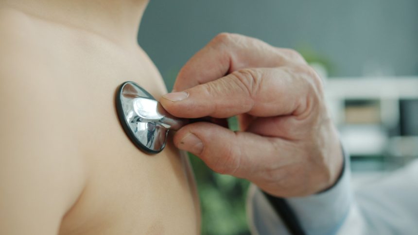 Médico ausculta o peito de uma criança com um estetoscópio em ambiente clínico.