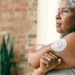 Mulher adulta com sensor contínuo de glicose fixado no braço.