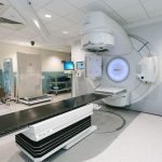 Acelerador linear de radioterapia em uma sala hospitalar preparada para tratamento oncológico.