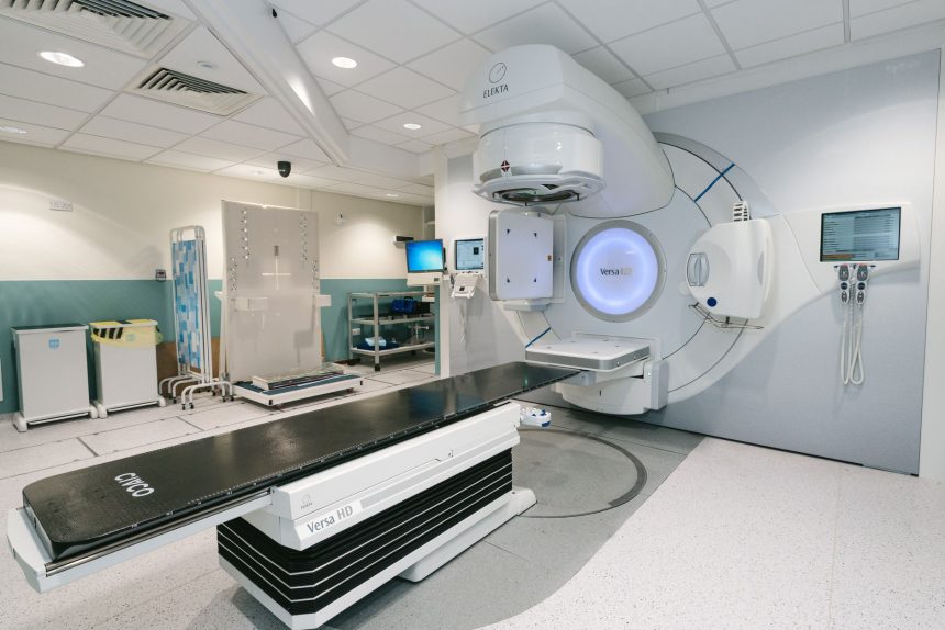 Acelerador linear de radioterapia em uma sala hospitalar preparada para tratamento oncológico.