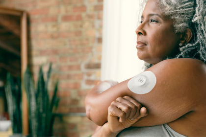 Mulher adulta com sensor contínuo de glicose fixado no braço.