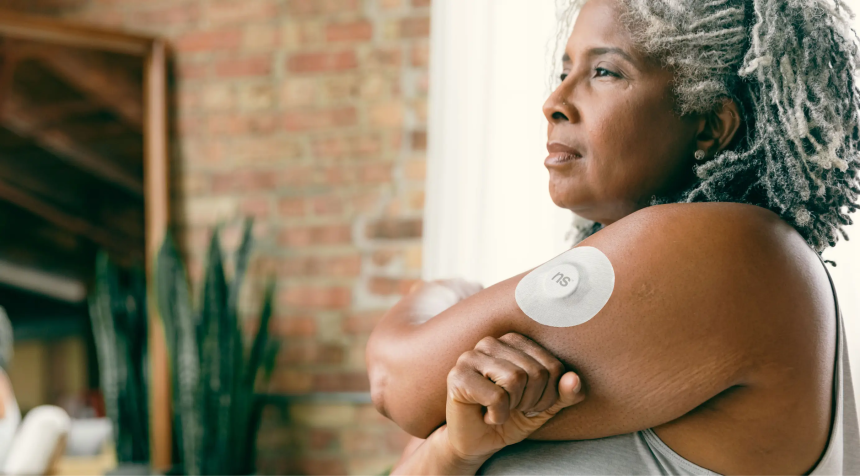 Mulher adulta com sensor contínuo de glicose fixado no braço.